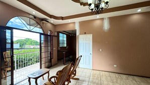 Una habitación amplia con balcón, ventilador de techo y una puerta con el número 7.