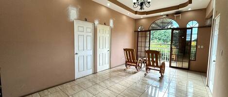 A spacious hallway with tiled flooring, two white doors, and a chandelier.