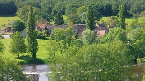Un village rural avec des maisons traditionnelles, une rivière et une végétation luxuriante tout autour.