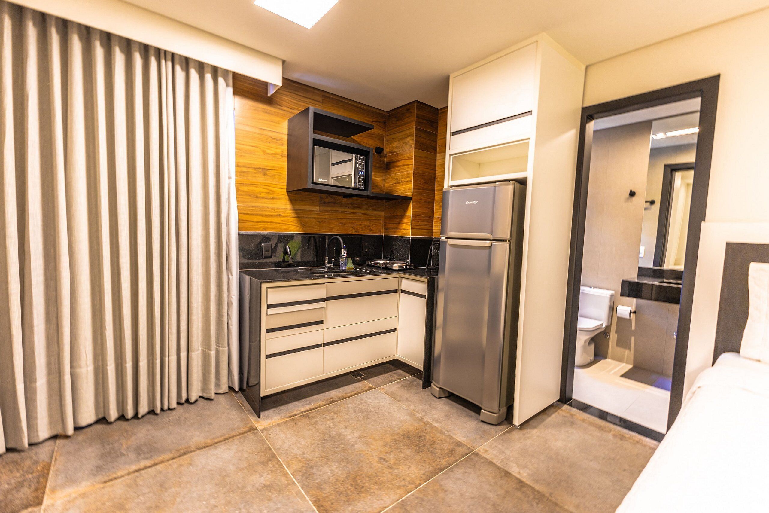 Une chambre d’hôtel compacte équipée d’une kitchenette, d’un réfrigérateur, d’un four à micro-ondes, d’un évier et de toilettes.