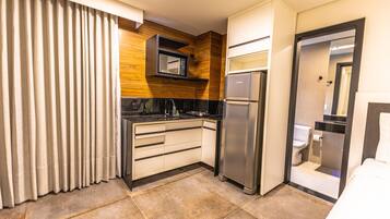 Une chambre d’hôtel compacte équipée d’une kitchenette, d’un réfrigérateur, d’un four à micro-ondes, d’un évier et de toilettes.