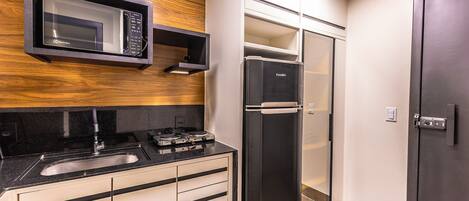 Una cocina compacta con microondas, estufa, lavaplatos y refrigerador.