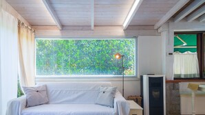 Una habitación con un sofá blanco, una lámpara de pie, un calentador y una ventana con persianas.