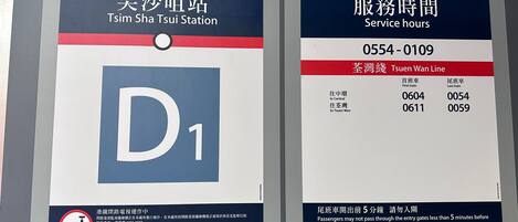 A signboard with service hours and train schedules for Tsuen Wan Line at Tsim Sha Tsui Station.