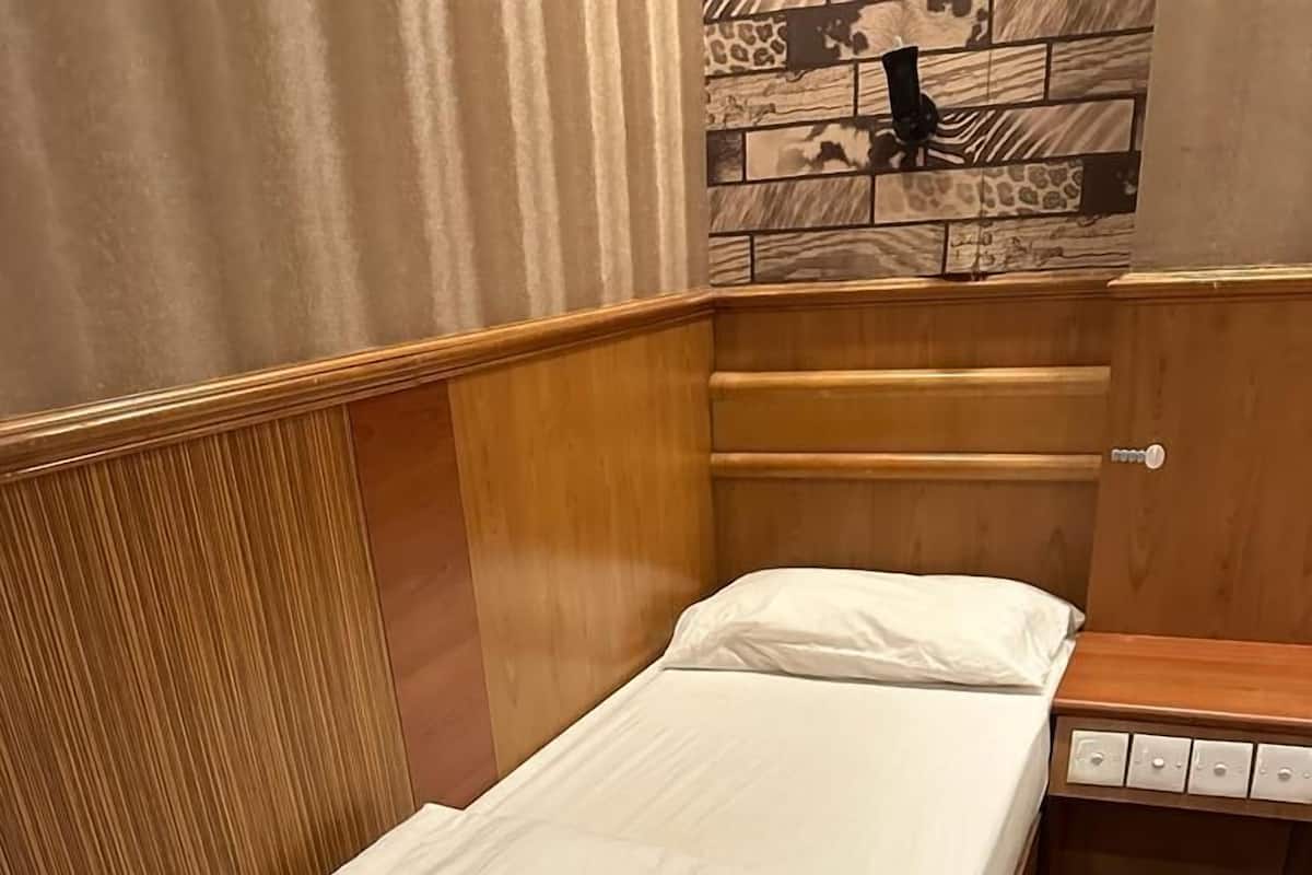 Ein Einzelbett mit weißer Bettwäsche in einem Raum mit Holzwänden und einer gefliesten Wand.