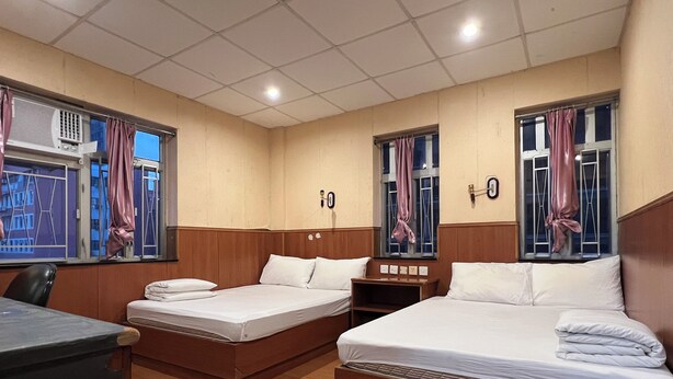 Een hotelkamer met twee bedden, een bureau en een raam met gordijnen.