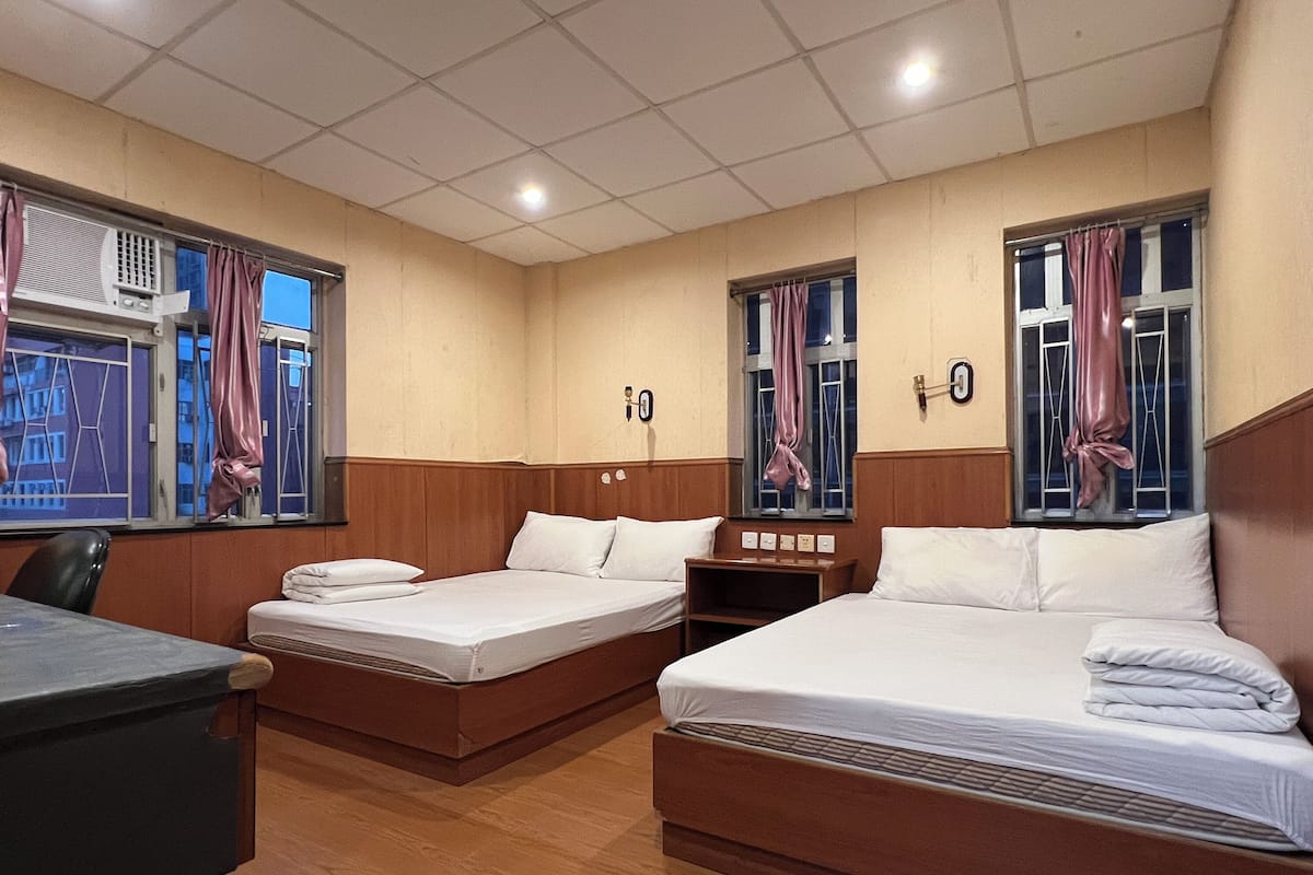 Ein Hotelzimmer mit zwei Betten, einem Schreibtisch und einem Fenster mit Vorhängen.