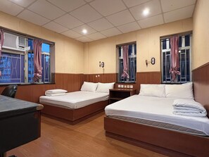 Quarto de hotel com duas camas, uma escrivaninha e janela com cortinas.