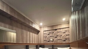 Een hotelkamer met twee eenpersoonsbedden, een houten vloer, een wand met een patroon en een plafondlamp.