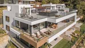 A modern multi-story house with a glass balcony, outdoor seating, and a view of the surrounding landscape. - Venere | Luxury Penthouse Rooftop Pool Spa (Marbella)