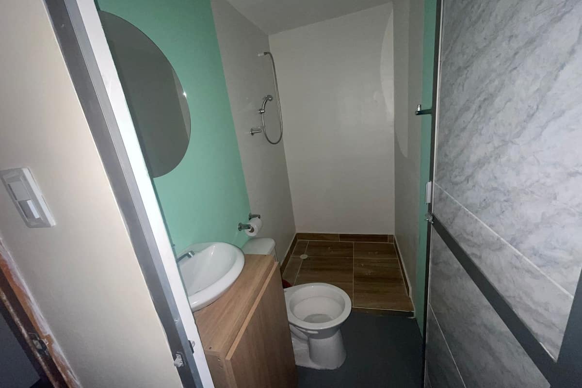 A small bathroom with a sink, toilet, and shower.