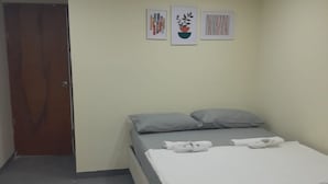 A bedroom with a bed, pillows, and a door. There are three framed pictures on the wall. - Miramar Baru (Cartagena)