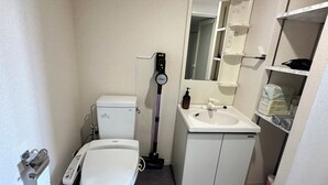 Pieni, siisti kylpyhuone, jossa on wc, pesuallas ja peili. Pesualtaalla on käsienkuivaaja ja saippuapullo.