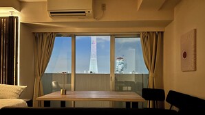 Hotellihuone, jossa on suuri ikkuna, josta avautuu näkymä korkeaan torniin ja muihin rakennuksiin.