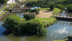 A serene landscape with a pond, lush greenery, and a white building with a balcony. - BonitaVillageLasTerrenas 4Beds8Pax (Las Terrenas)