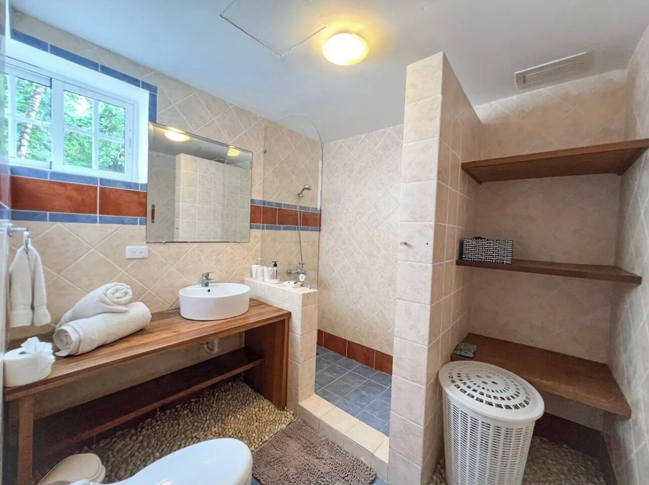 Een badkamer met een houten wastafelmeubel, een wastafel, een spiegel, een douche en een toilet.