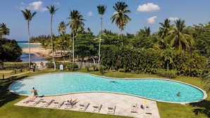 A swimming pool with lounge chairs, palm trees, and a beach view. - BonitaVillageLasTerrenas 4Beds8Pax (Las Terrenas)