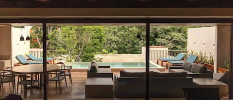 Un espacio exterior moderno con piscina, mobiliario y vista a exuberante vegetación.