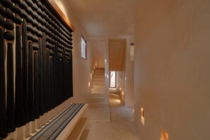 A hallway with a patterned wall, a staircase, and a door leading to another room.