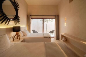A hotel room with two beds, a large mirror, a lamp, a window with curtains, and a small shelf.