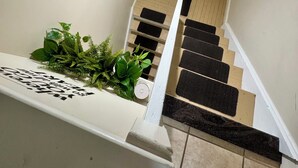 A staircase with a 'Welcome' sign, a plant, and a white wall.