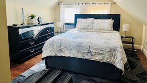 A bedroom with a bed, a dresser, a nightstand, a lamp, and a wall with a motivational quote.
