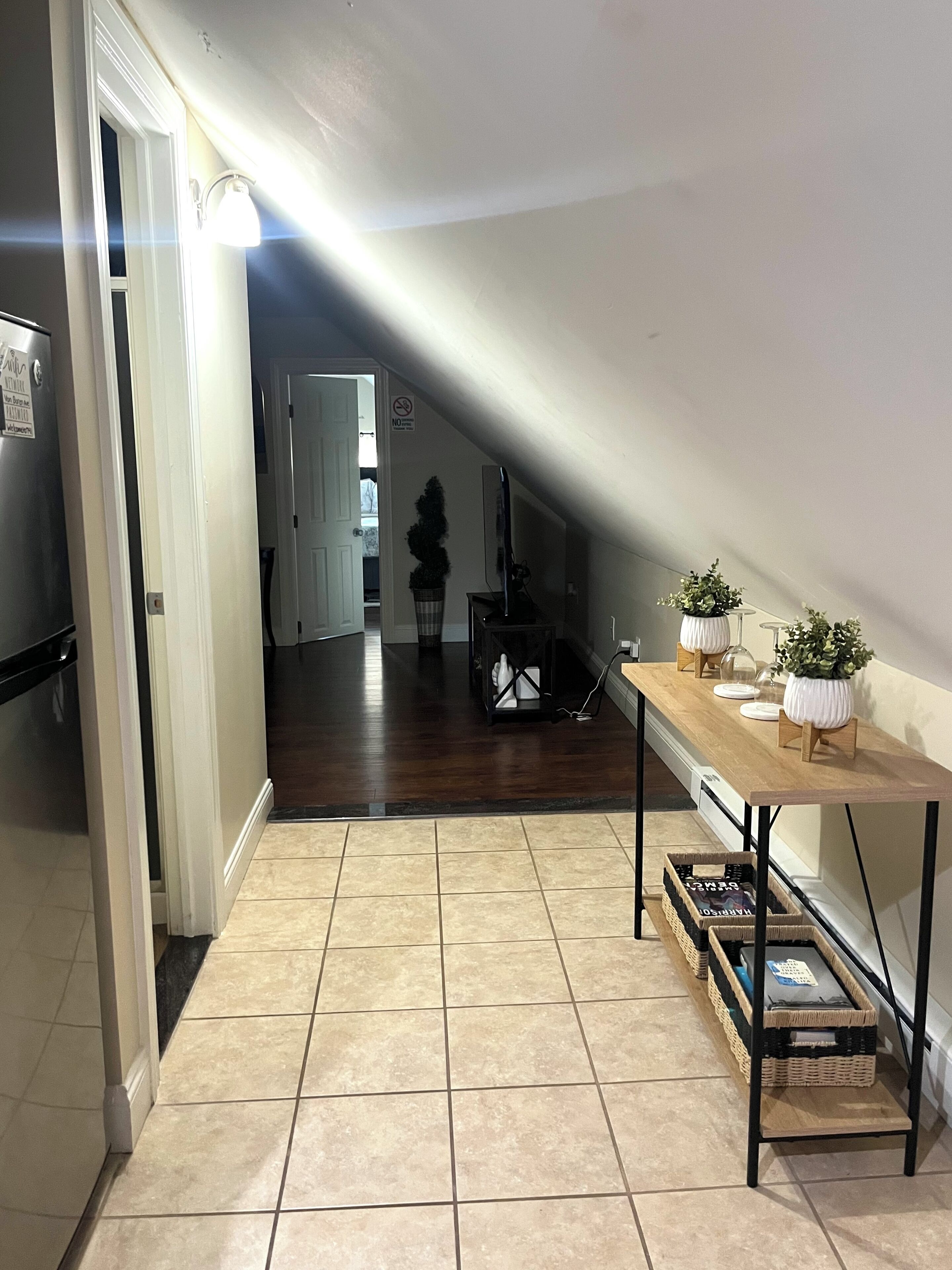 A kitchen with a wooden table, potted plants, and a refrigerator.