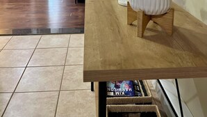 A spacious living area with a wooden dining table, potted plants, and a television.