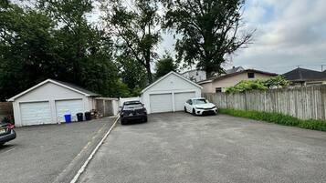 Eine Garage mit zwei Autos, umgeben von Bäumen und einem Holzzaun.