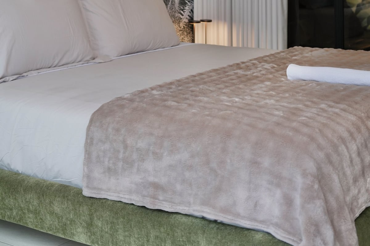 Ein Bett mit dunkelgrüner Kopfteil, einer beigen Decke und einer Wandmalerei.