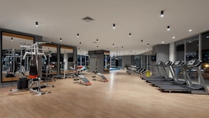 Uma academia moderna com equipamentos de cardio, máquinas de peso e espelhos.