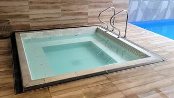 Una piscina interior rectangular con borde de azulejos y barandillas de metal.
