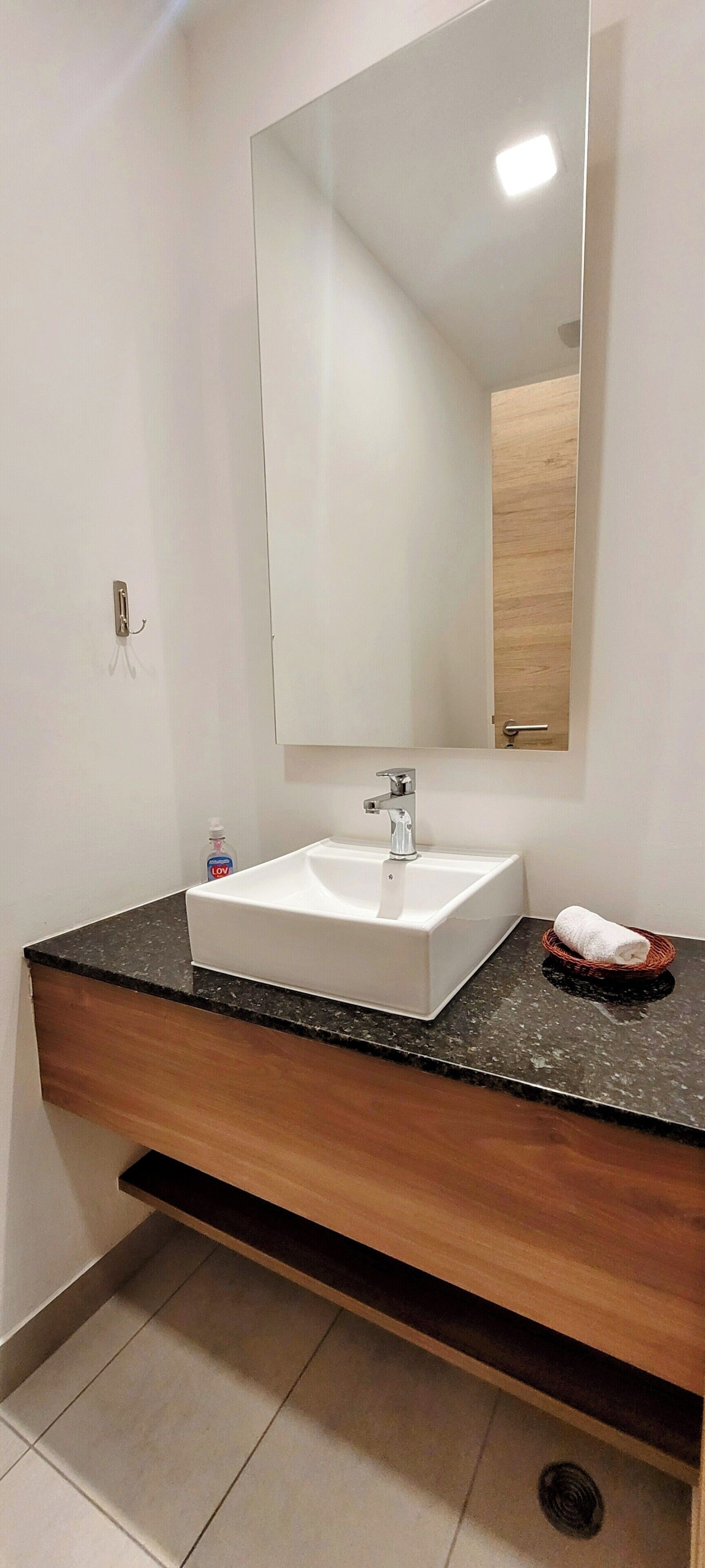 A bathroom with a white sink, a large mirror, and a wooden vanity.