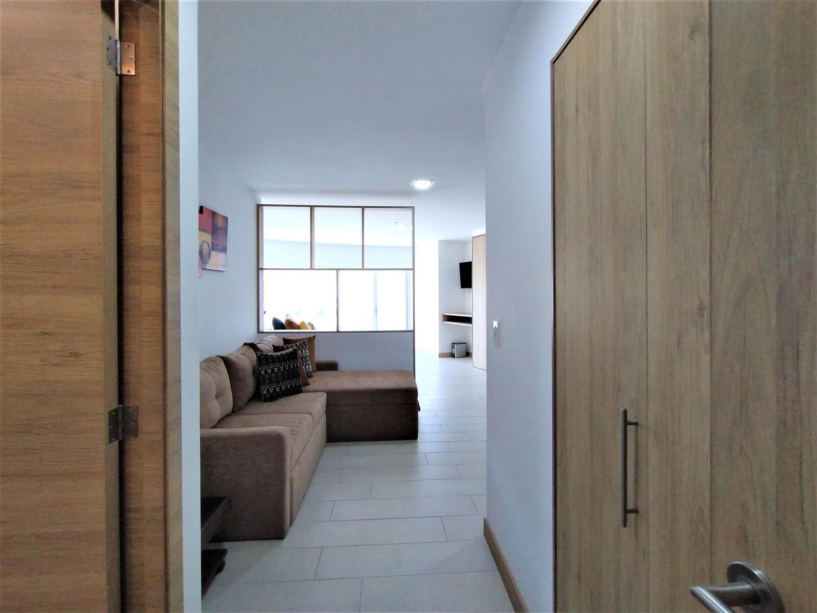 A modern living room with a sofa, a window, and a wardrobe.