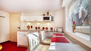 A modern kitchen with white cabinets, a microwave, and a dining area with a table and chairs. - Apartment 'Ferienwohnung Bleichen 14' with Shared Pool, Shared Garden and Wi-Fi (Stralsund)