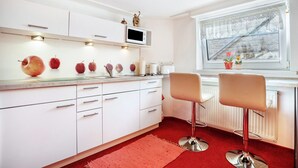 A modern kitchen with white cabinets, a microwave, and a window with a view of a snowy landscape. - Apartment 'Ferienwohnung Bleichen 14' with Shared Pool, Shared Garden and Wi-Fi (Stralsund)