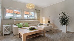 Moderni olohuone, jossa on sohva, sohvapöytä ja ruukussa oleva kasvi.