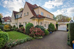 A two-story house with a paved driveway and a well-maintained garden. - Apartment 'Ferienwohnung Bleichen' with Private Pool, Shared Garden and Wi-Fi (Stralsund)