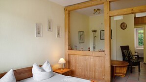 Een slaapkamer met een bed, bedlampje, houten hoofdeinde en een spiegel.