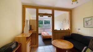 Een kamer met een bed, een houten bureau, een bank en een klein tafeltje.