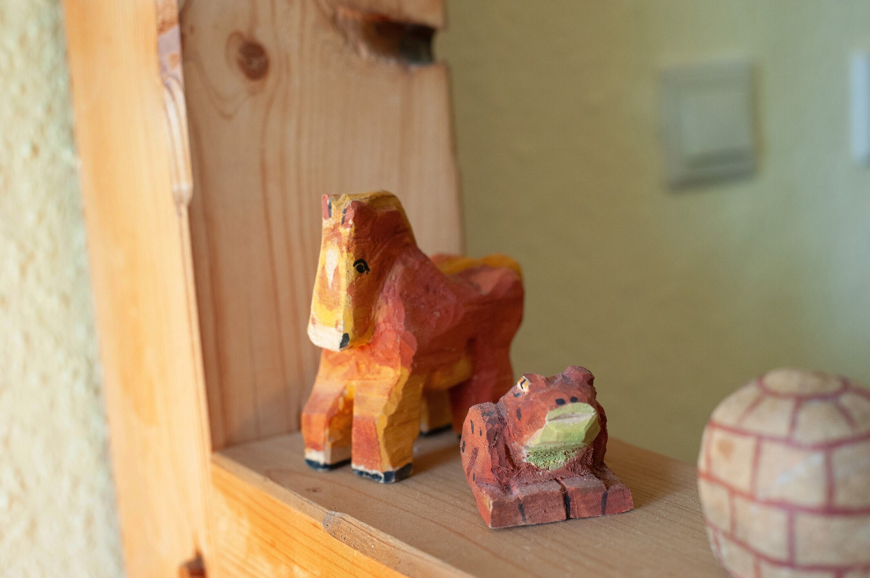 A wooden horse figurine on a shelf, a small bear figurine, and a globe.