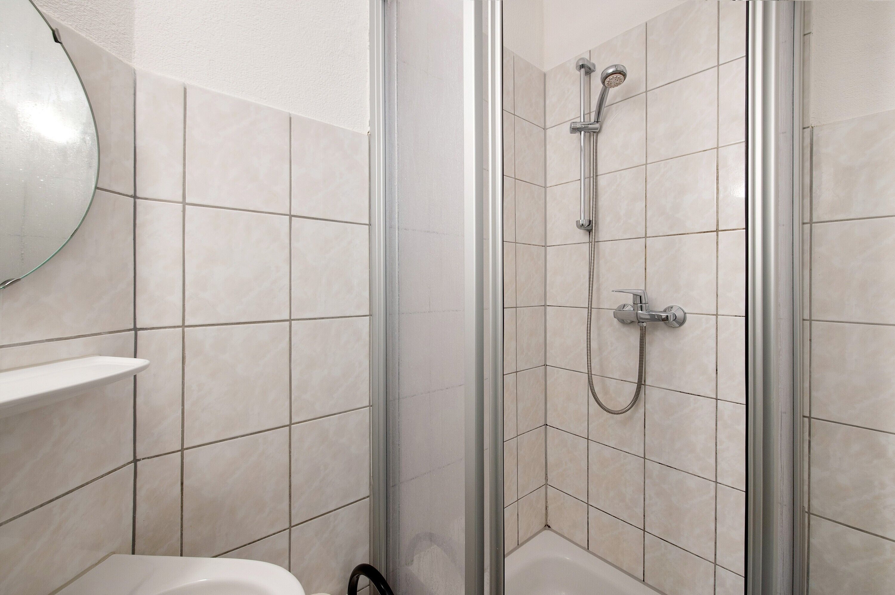 Un baño con ducha de vidrio, inodoro y espejo.