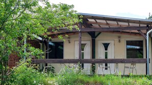 Un edificio con un patio cubierto, una pared de ladrillo y una ventana con marco blanco.