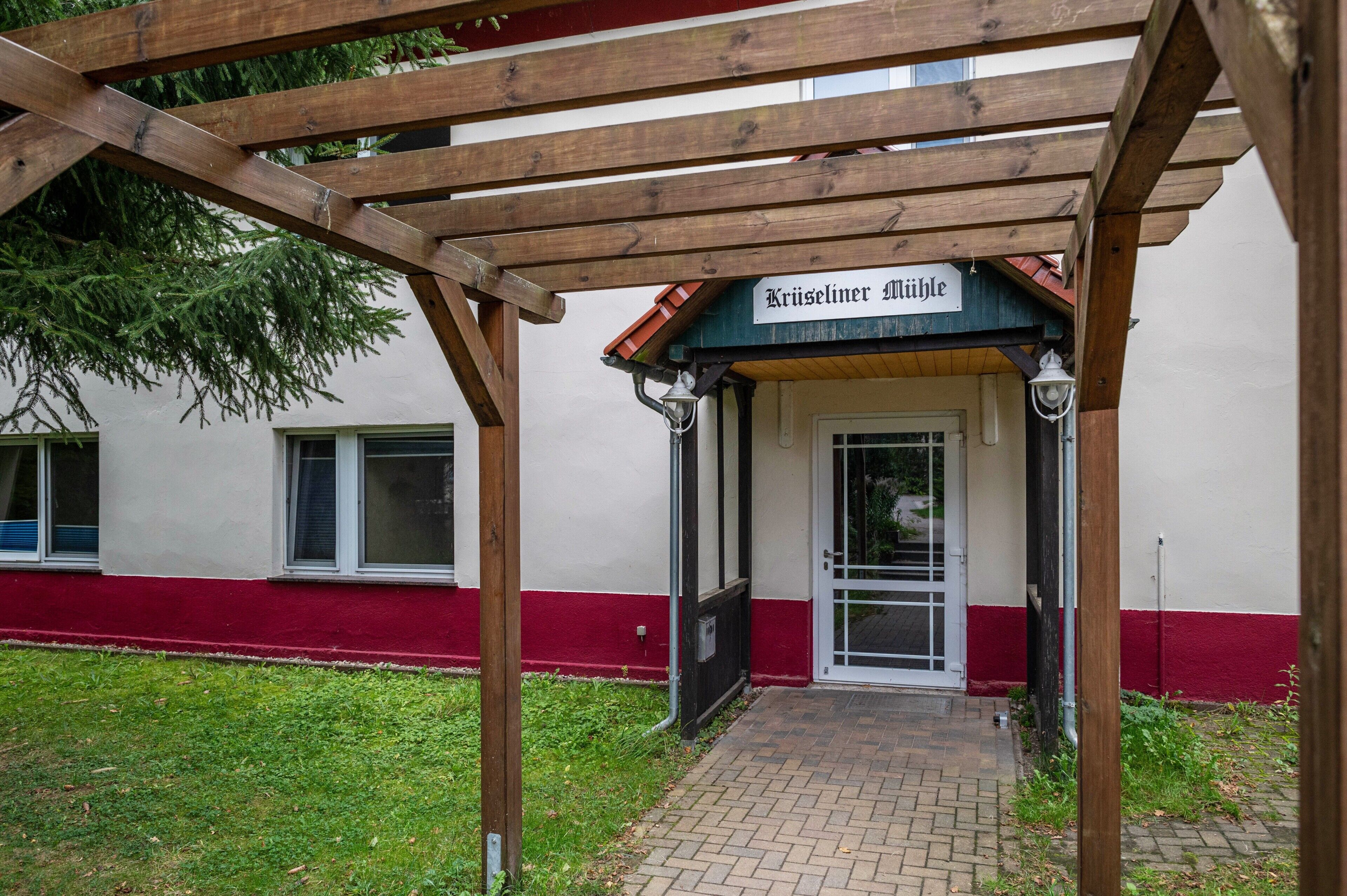 Un edificio con un cartel que dice 'Kreiseliner Milbe' bajo una pérgola de madera.