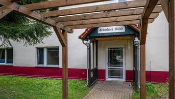 Un edificio con un cartel que dice 'Kreiseliner Milbe' bajo una pérgola de madera.