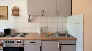 Una cocina con estufa, lavaplatos, alacenas y cafetera.