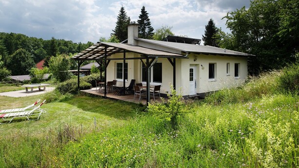 A house with a covered patio, a lawn, and a garden. - Holiday home 'Rethra Nord' with private terrace and WLAN (Feldberger Seenlandschaft)