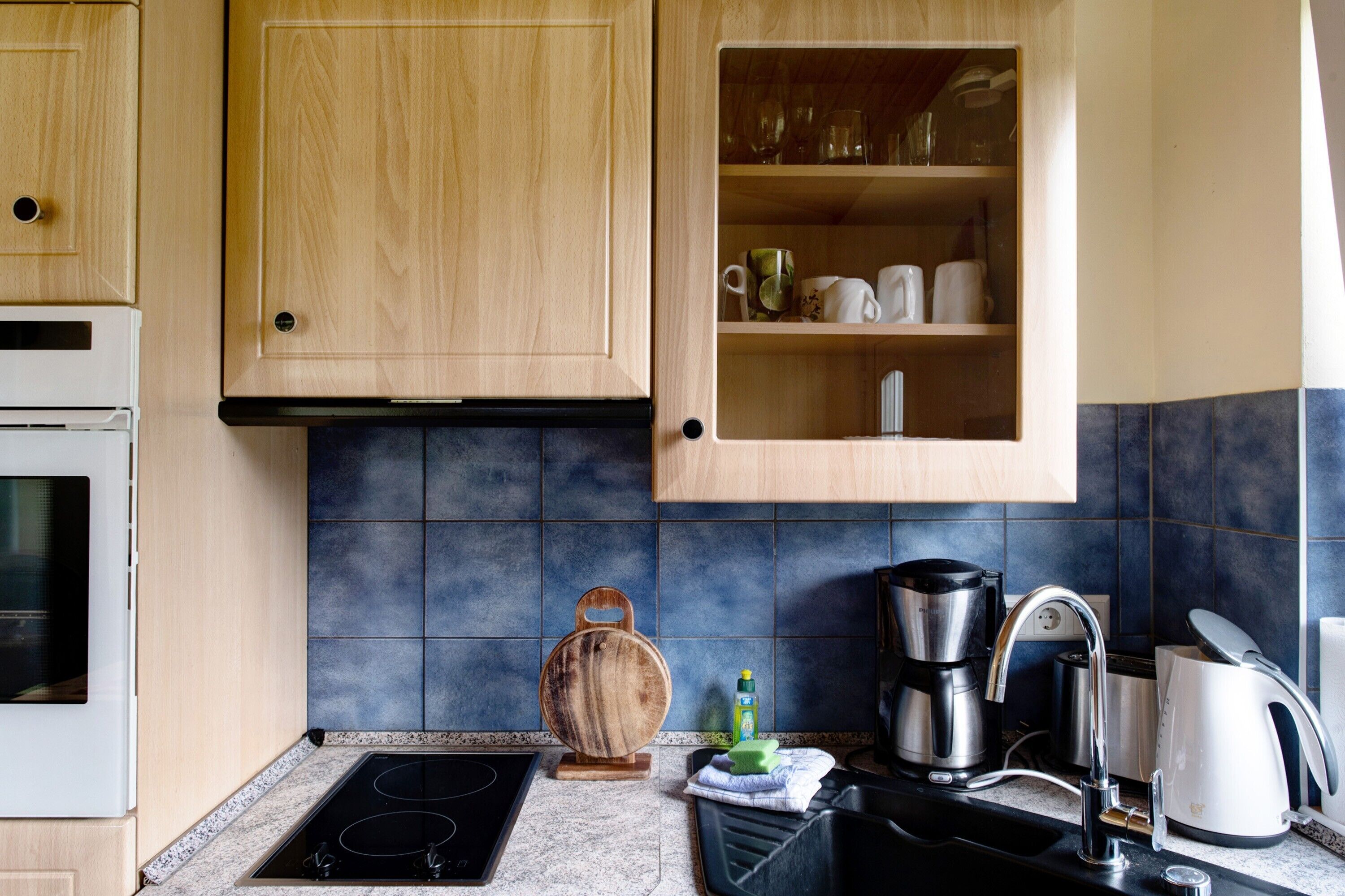 A kitchen with wooden cabinets, a built-in microwave, a coffee maker, and a kettle.