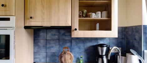 A kitchen with wooden cabinets, a built-in microwave, a coffee maker, and a kettle.