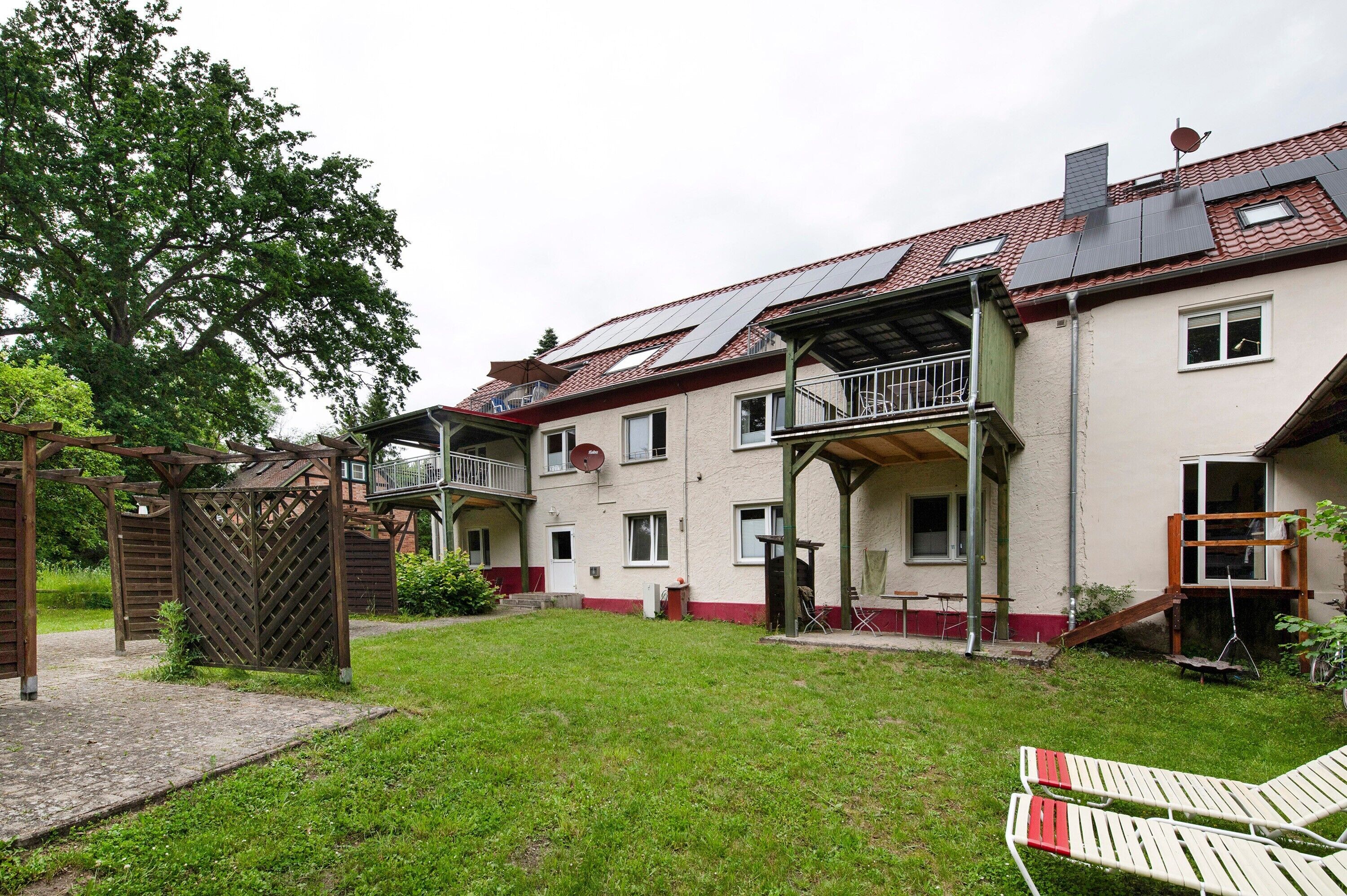Ein zweistöckiges Haus mit überdachter Terrasse, Holzzaun und Rasengarten.
